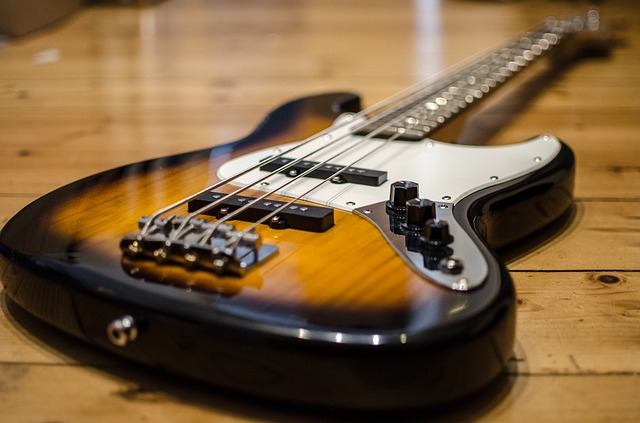 Ein braun-weißer E-Bass liegt auf einem Holzboden.